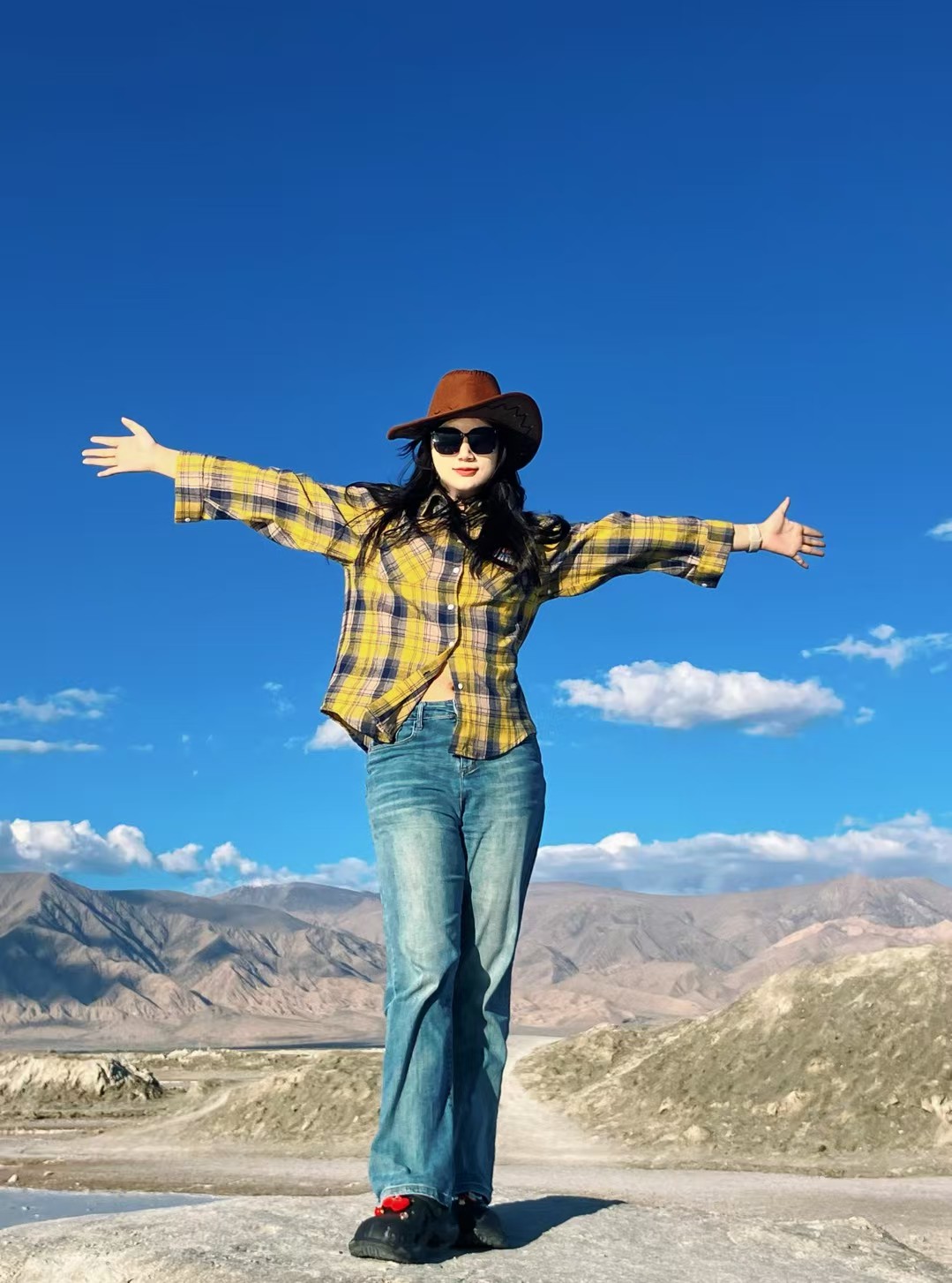 Xinyi Zhang standing against a blue mountain sky