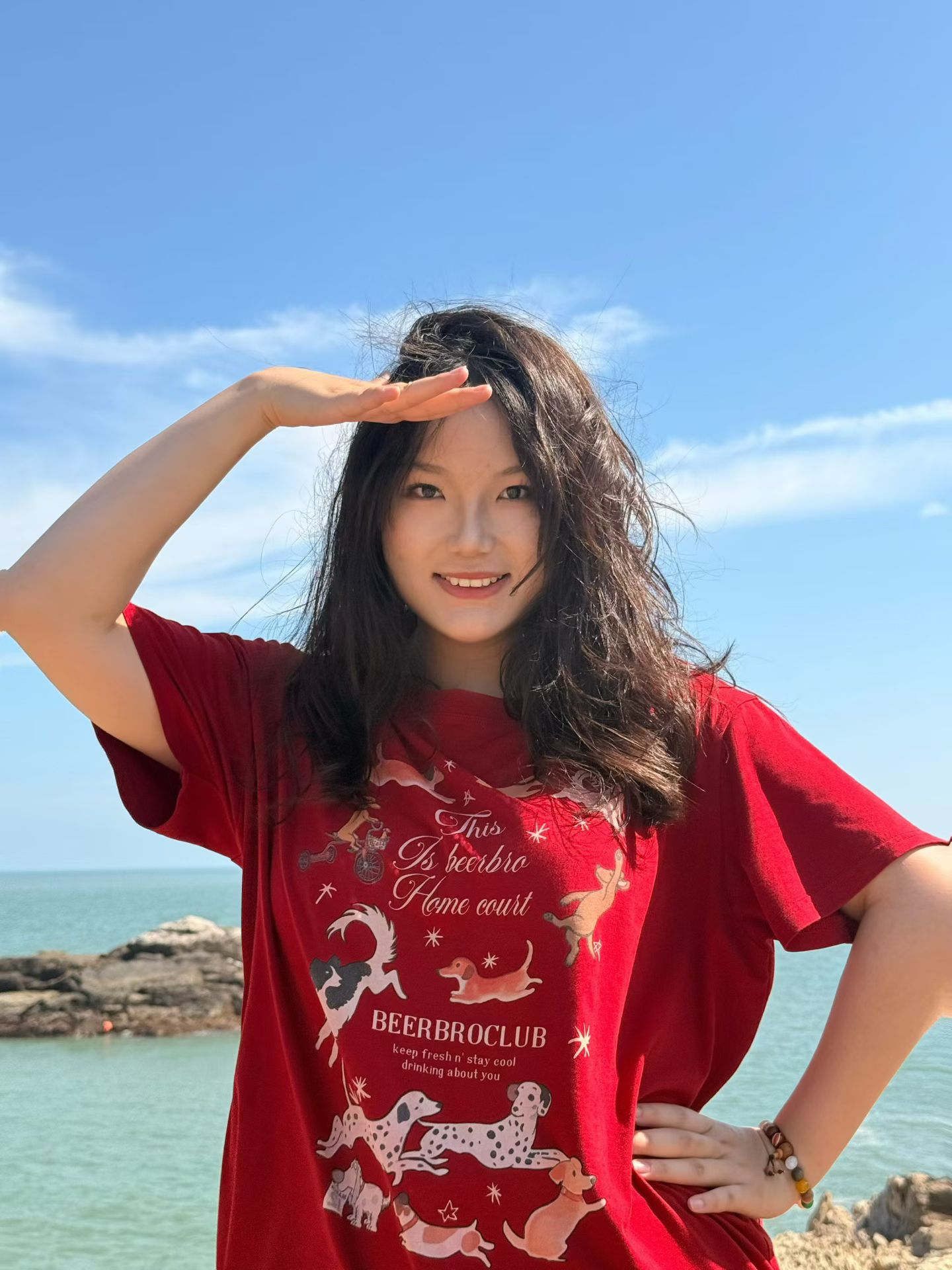 Xinyi Zhang by the sea under a bright blue sky